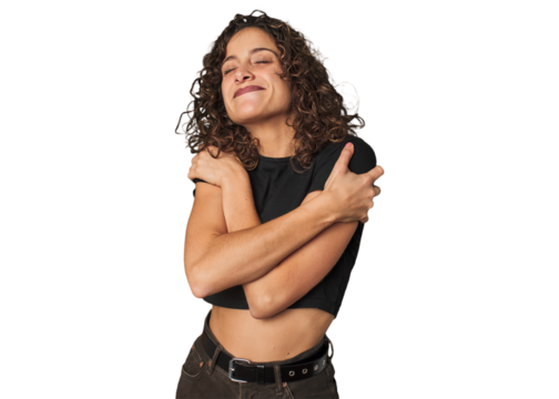 Radiant young woman with stunning curls hugs, smiling carefree and happy.