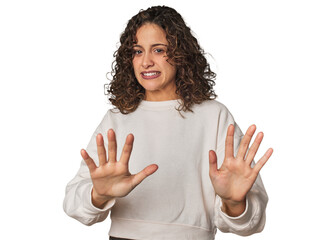 Radiant young woman with stunning curls rejecting someone showing a gesture of disgust.