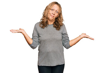 Middle age blonde woman wearing casual clothes clueless and confused expression with arms and hands...
