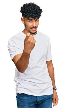 Young arab man wearing casual white t shirt beckoning come here gesture with hand inviting welcoming happy and smiling
