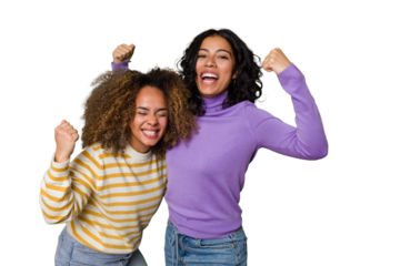 Two female friends isolated in studio raising fist after a victory, winner concept.