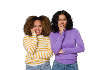 Two female friends isolated in studio biting fingernails, nervous and very anxious.