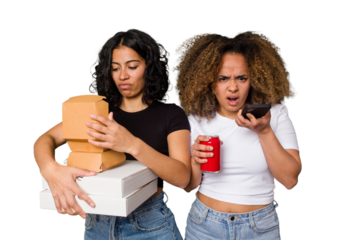 Two young women, one Latina and one with Afro hair, laugh as they hold pizzas and burgers from a recent delivery. 