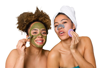 Two friends pamper themselves with facial treatments for a relaxing spa day at home, with laughter...