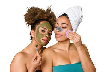 Two friends pamper themselves with facial treatments for a relaxing spa day at home, with laughter...