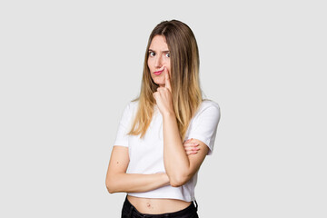 Fototapeta premium Young blonde posing for a portrait isolated, exuding natural beauty and radiance unhappy looking in camera with sarcastic expression.