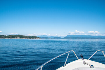 Fototapeta premium Bow of Boat Looking Towards Tropical Mountains & Island on Summer Day Along Strait of Georgia in Vancouver Island, British Columbia, Canada