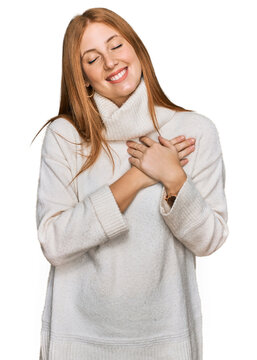 Young irish woman wearing casual winter sweater smiling with hands on chest with closed eyes and grateful gesture on face. health concept.