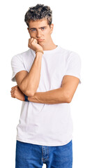 Young handsome man wearing casual white tshirt thinking looking tired and bored with depression problems with crossed arms.