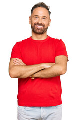 Handsome middle age man wearing casual red tshirt happy face smiling with crossed arms looking at...