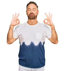 Naklejka premium Handsome middle age man wearing casual tie dye tshirt relax and smiling with eyes closed doing meditation gesture with fingers. yoga concept.