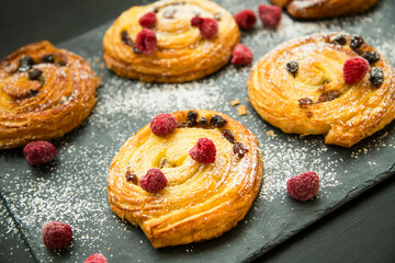 Freshly baked pastry rolls with vanilla, raisins and fresh raspberries - 577525478