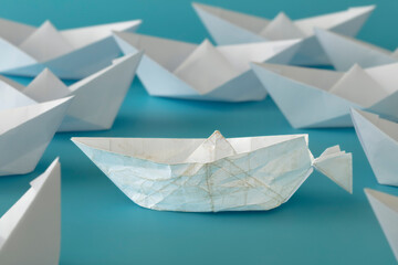 White paper boat almost destroyed on whites paper boats on blue background. concept: keep going, be brave, courage, motivation, feel especial. 