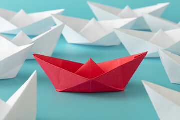 Red color paper ship on blue background on white paper boats. Concept: Make the difference, be...