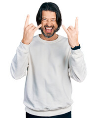 Middle age caucasian man wearing casual clothes shouting with crazy expression doing rock symbol with hands up. music star. heavy music concept.