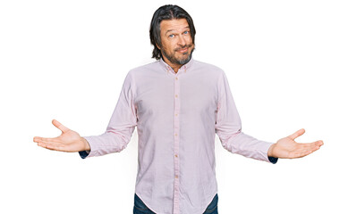 Middle age handsome man wearing business shirt clueless and confused expression with arms and hands raised. doubt concept.