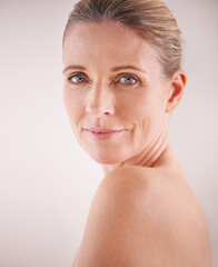 You can tell she loves her skin. Cropped studio shot of a beautiful mature woman looking over her...