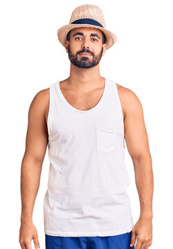 Young hispanic man wearing casual summer hat relaxed with serious expression on face. simple and natural looking at the camera.