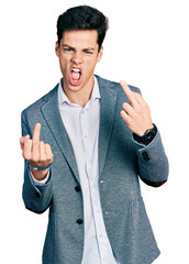 Young hispanic man wearing business clothes showing middle finger doing fuck you bad expression,...