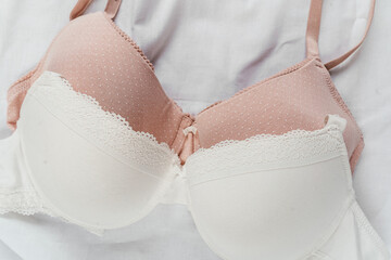 White and pink bras on the bed. Women tender lingerie, underwear. Top view, close up. Flat lay,...