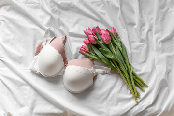 White and pink bra, tulips on the bed. Women tender lingerie, underwear. Top view, close up. Flat lay, beauty blog or social media minimal concept. Present for Valentines, Women’s day	
