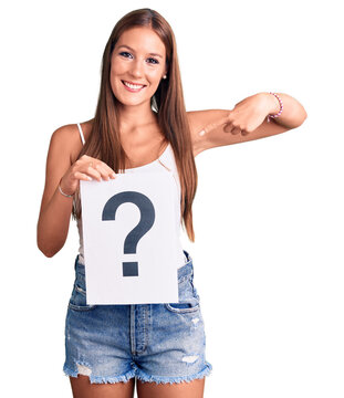 Young beautiful hispanic woman holding question mark pointing finger to one self smiling happy and proud