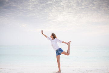 Fototapeta na wymiar woman doing yoga by the sea pastel colors
