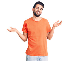 Young handsome man with beard wearing casual t-shirt smiling showing both hands open palms, presenting and advertising comparison and balance