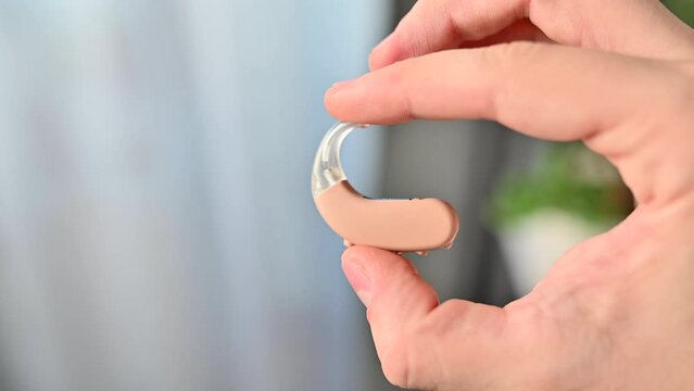 Close up of man  holding hearing aid equipment. The hearing aid lies in the man palm. Hearing aid concept. Man holding hearing aid equipment.