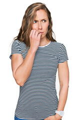Young blonde woman wearing casual clothes looking stressed and nervous with hands on mouth biting nails. anxiety problem.