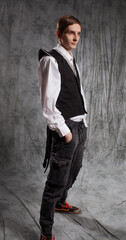 Stylish and elegant young man in a Gothic vest , studio portrait on gray