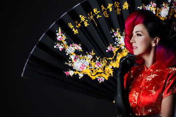 A young multiethnic woman in a bright Asian costume. voluminous hairstyle with scarlet hair and...