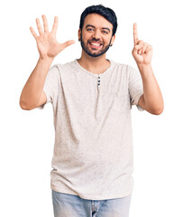 Naklejka premium Young hispanic man wearing casual clothes showing and pointing up with fingers number six while smiling confident and happy.