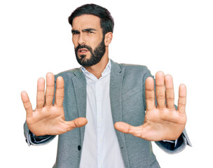 Young hispanic man wearing business clothes doing stop gesture with hands palms, angry and...