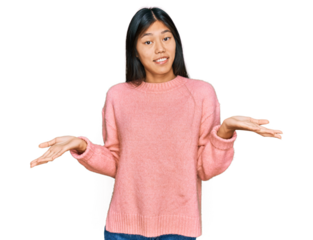 Beautiful young asian woman wearing casual winter sweater clueless and confused expression with arms and hands raised. doubt concept.