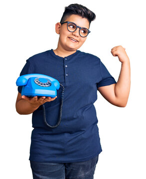 Little boy kid using vintage telephone pointing thumb up to the side smiling happy with open mouth
