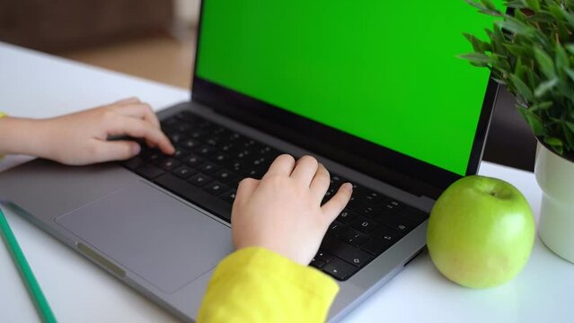 Cute smart caucasian primary School Child typing on the keyboard laptop. Online tutor teaching digital class, web lesson programming on computer at home. Virtual education. Schoolboy girl studying