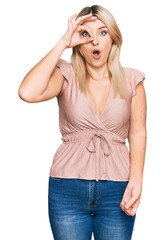 Young caucasian woman wearing casual clothes doing ok gesture shocked with surprised face, eye looking through fingers. unbelieving expression.