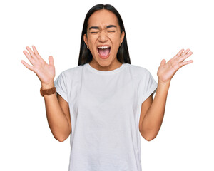 Young asian woman wearing casual white t shirt celebrating mad and crazy for success with arms...