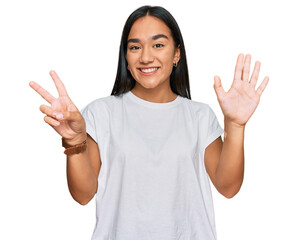 Young asian woman wearing casual white t shirt showing and pointing up with fingers number seven...
