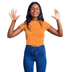 Young indian girl wearing casual clothes and glasses showing and pointing up with fingers number...