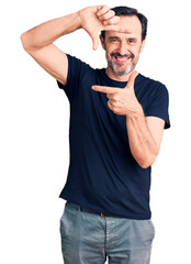 Middle age handsome man wearing casual t-shirt smiling making frame with hands and fingers with happy face. creativity and photography concept.