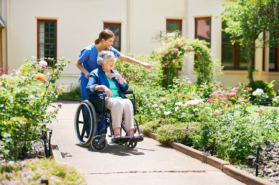 Naming the flowers as they go. Shot of a resident and a nurse outside in the retirement home garden.