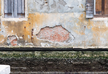 Opening on a wall of a house in Venice. You can see the bricks and the details of the wall. Yellow and highly detailed texture.