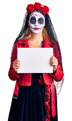 Woman wearing day of the dead costume holding blank empty banner thinking attitude and sober expression looking self confident