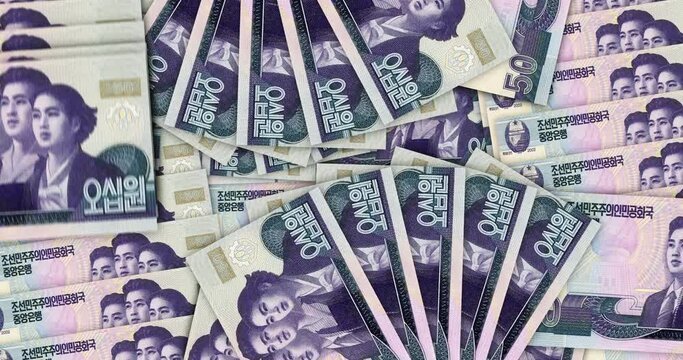 North Korea Won banknotes in a cash fan mosaic pattern loop. North Korean KPW 50 notes. Abstract concept of bank, finance, economy seamless and looped decorative design background. 