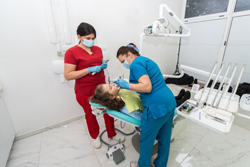 Dentist appointment at a dental clinic, placing braces locks on the teeth and pulling the archwire...