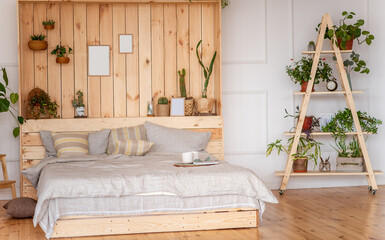 Bedroom in rustic style. Scandinavian interior with large bed with wooden wall. Staircase with house flowers in terracotta pots. Botanical apartments. Natural fabrics, eco design. Mock up template
