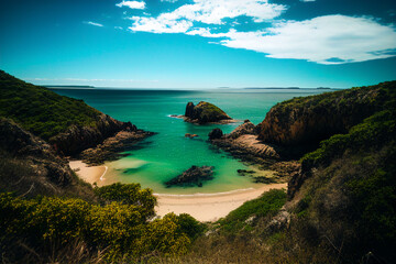 Fototapeta premium Baia do Sancho. Sancho Beach (Praia do Sancho) in Fernando de Noronha Island Brazil. Exotic beach on islands. Rocky shore in ocean. Rock Pools sea. Coast Scenic Mountains. AI Generative Illustration.