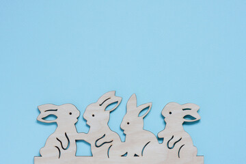 Flat wooden craft blank in shape of bunnies on pastel blue background. Happy Easter concept. Mockup for greeting card with space for text. top view, flat lay